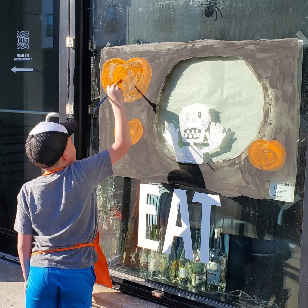 A little boy paints a Halloween scene on a Pittsburg, KS business' window.